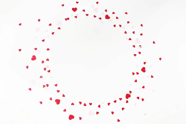 Día de San Valentín o composición festiva de la boda. Círculo hecho de confeti en forma de corazón de papel rojo y rosa aislado sobre fondo de mesa blanco. Decoración de fiesta, concepto de celebración. Piso tendido, vista superior . —  Fotos de Stock