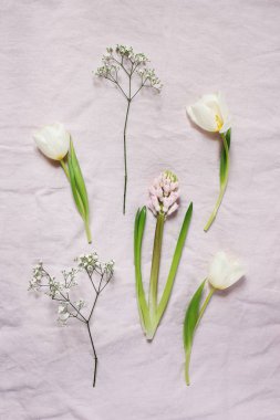Bahar, Paskalya çiçek botanik kompozisyon. Beyaz Gypsophila, lale ve sümbül çiçekleri pembe keten masa örtüsü arka plan üzerinde yalan. Stok fotoğraf tarz. Dikey düz yatıyordu, en iyi görünüm.
