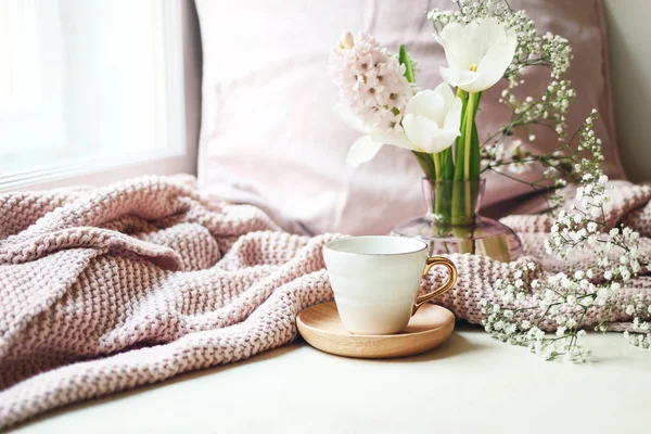 Páscoa acolhedora, primavera ainda cena da vida. Xícara de café, xadrez de malha rosa e buquê floral em vaso no peitoril da janela. Vintage foto estilo feminino. Composição com tulipas, jacinto e Gypsophila — Fotografia de Stock