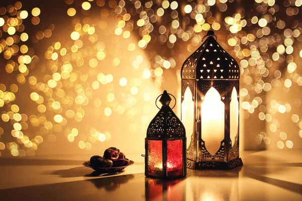 Prydnads arabiska lyktor med brinnande ljus. Glittrande gyllene bokeh lampor. Tallrik med datum frukt på bordet. Gratulationskort för muslimska semestern Ramadan Kareem. Iftar middag bakgrund. — Stockfoto