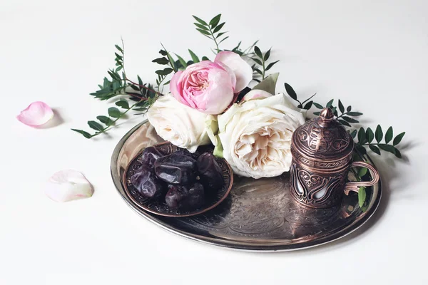라마단 카림 인사말 카드, 초대장입니다. 오래 된 은색 쟁반에 녹색 지점, 핑크 장미, 청동 커피 컵, 날짜 과일 접시. 화이트 테이블 배경입니다. 이슬람 Iftar 저녁 식사입니다. Eid ul Adha 배너. — 스톡 사진