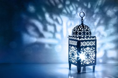 Parlayan mum yanan ile Fas fener silüeti. Dekoratif gölgeler. Bayram tebrik kartı, Müslüman kutsal ay Ramazan Kareem için davet. Mavi gece arka plan bokeh ışıklar ile.