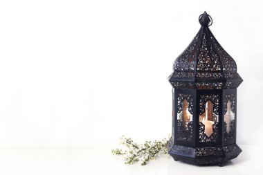 Süs siyah Fas, beyaz masa üzerinde çiçekaçan prunus ağaç dalları ile Arap fener. Müslüman toplum kutsal ay Ramazan Kareem için tebrik kartı. Şenlikli arka plan.