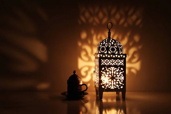Silhueta de lanterna ornamental marroquina brilhante com xícara de chá de bronze. Sombras decorativas douradas. Cartão de saudação, convite para o mês sagrado muçulmano Ramadã Kareem. Fundo da noite festiva . — Fotografia de Stock