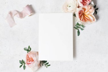 Feminen düğün, Doğum günü kırtasiye model sahnesi. Yeşil yaprakları, allık pembe Ingiliz güller ve Ranunculus çiçekler Buket ile boş kağıt tebrik kartı. Beton tablo arka plan. Düz yatıyordu, üst