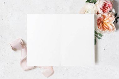 Düğün, Doğum günü kırtasiye model sahnesi. Boş açık katlanmış tebrik kartı. Dekoratif çiçek köşesi. Yeşil yaprakları, allık pembe Ingiliz güller ve Ranunculus çiçekler. Beton tablo arka plan. Yatık
