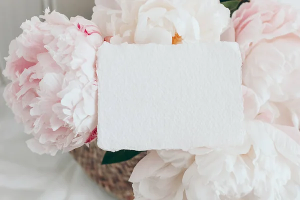 Casamento feminino, cena de aniversário. Closeup de cartão de papel de algodão em branco, convite em pétalas florais rosa. Flores de peónia, flores. Primavera floral, composição. Deitado plano, vista superior . — Fotografia de Stock