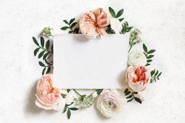 Kadınsı düğün, doğum günü modeli. Boş kağıt tebrik kartı. Çiçekli beyaz ve pembe renunculus, karanfil ve astrantia çiçekleri. Mercimek yaprakları. Beton masa arka planı. Düz yatış, üst görünüm