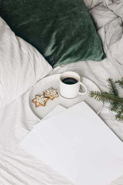 Natal festivo ainda vida. Papéis em branco convites mockups com xícara de café, biscoito de gengibre e ramos de abeto na placa de cerâmica. Fundo de férias. Pequeno-almoço na cama. Vertical. — Fotografia de Stock