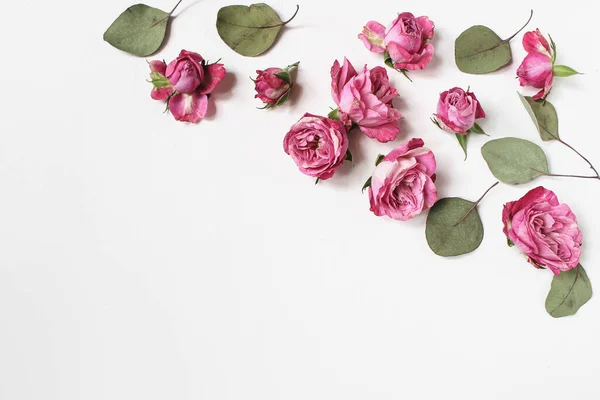 Composition féminine de bureau de mariage avec des fleurs roses roses, feuilles d'eucalyptus vert sec isolées sur fond de table blanc. Motif floral. Espace vide. Couché à plat, vue de dessus. Photo pour blog. — Photo