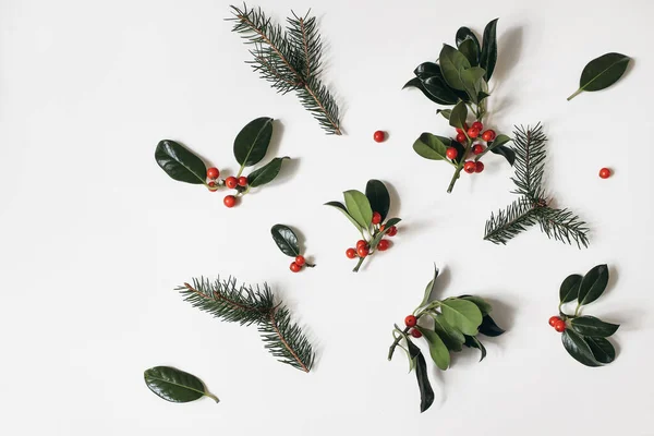 Julblommönster. Gräns ram av röda järnek bär och gröna gran grenar isolerad på vitt bord bakgrund. Vinter naturlig dekoration. Botanisk festlig platt låg, ovanifrån. — Stockfoto