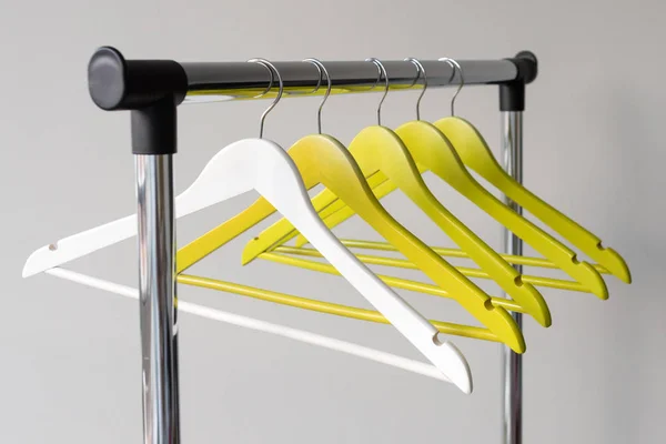 Lege kleerhangers op metalen spoor tegen een grijze achtergrond. Rechthoekig metalen kleding spoor met lege kleur houten kapstokken. — Stockfoto