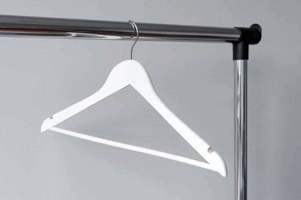 Lege kleding hanger op metalen spoor tegen een grijze achtergrond. Rechthoekig metalen kleding spoor met lege witte houten kapstok. — Stockfoto