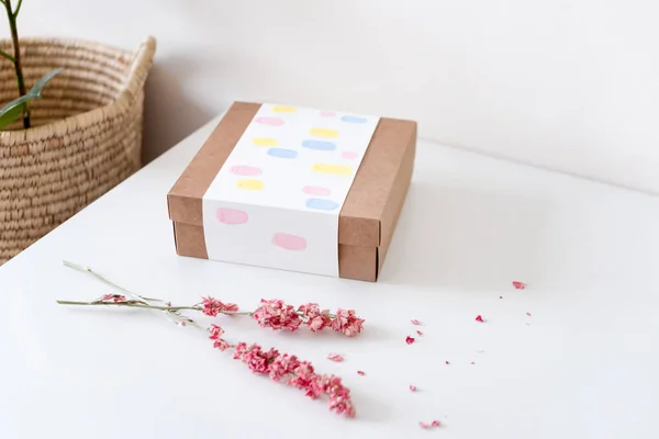 Caja de regalo de papel artesanal marrón con flores secas en mesa blanca. Enfoque selectivo . —  Fotos de Stock