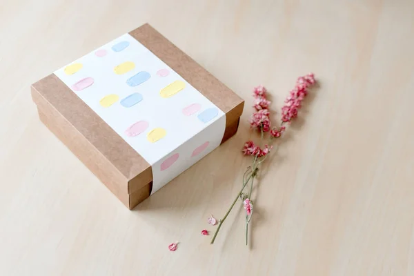Kahverengi craft kağıt hediye kutusu ahşap masa üzerinde kurutulmuş çiçekli. Seçici odak. — Stok fotoğraf