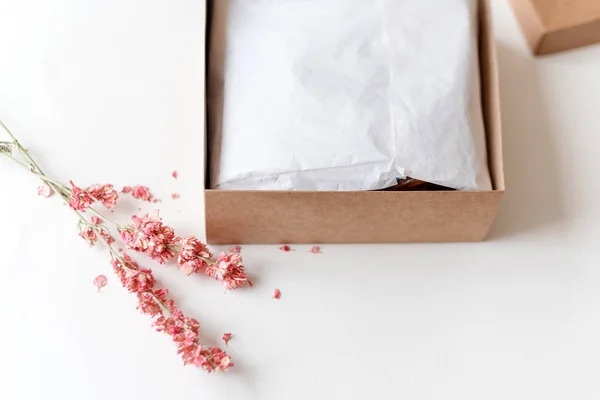 Caja de regalo de papel artesanal marrón con flores secas en mesa blanca. Enfoque selectivo . — Foto de Stock