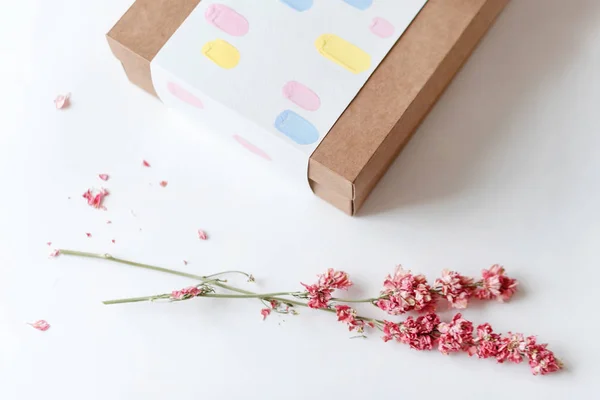 Kahverengi craft kağıt hediye kutusu beyaz masaya kurutulmuş çiçek ile. Seçici odak. — Stok fotoğraf