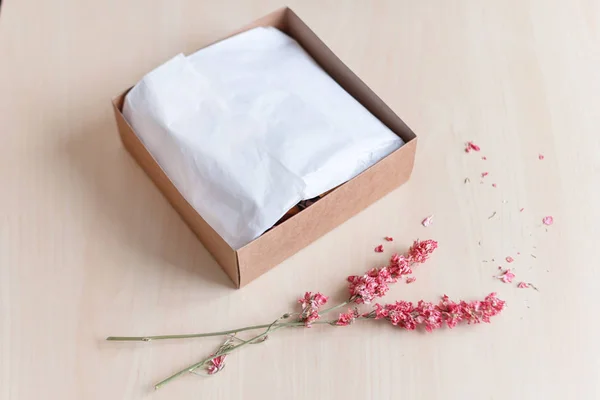 Caja de regalo de papel artesanal marrón con flores secas en mesa de madera. Enfoque selectivo . — Foto de Stock