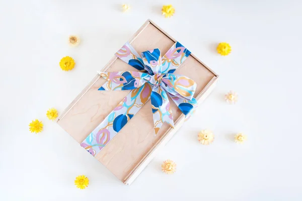 Coffret cadeau en bois avec arc et fleurs jaunes sur fond clair . — Photo