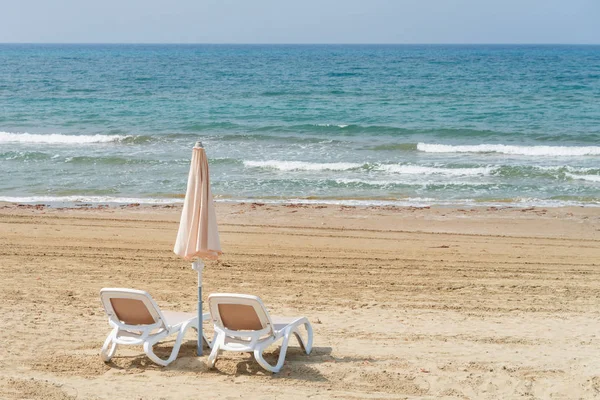 Parasole i sale leżak na plaży. Puste, plastikowe leżaki w pobliżu morza. Tropikalny wakacje, lato na tle. — Zdjęcie stockowe