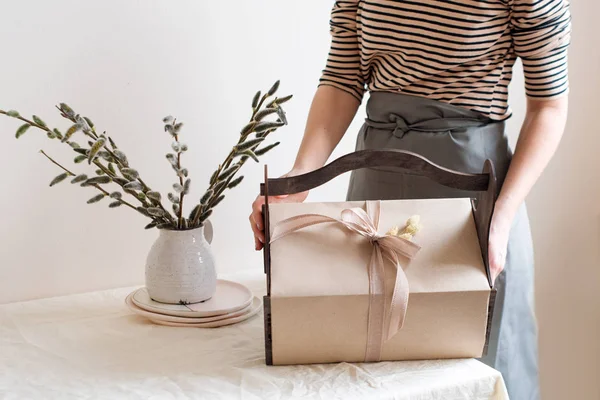 Caja de regalo en manos femeninas con flores de primavera sobre fondo de tela natural claro. Cesta de Pascua con regalos — Foto de Stock