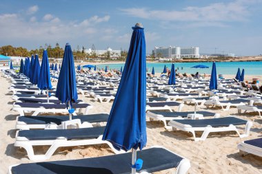 Plajda şemsiyeler ve şezlonglar bulunmaktadır. Denize yakın plastik şezlong. Tropikal tatil, yaz geçmişi.