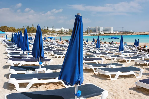 Umbrellas and chaise lounges on the beach. Plastic sunbeds near the sea. Tropical vacation, summer background. — Stock Photo, Image