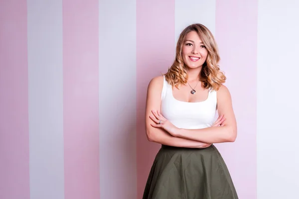 Linda mujer rubia natural sonriendo con dientes blancos perfectos y piel brillante. Sonriente joven rubia cabello mujer mirando a la cámara, mientras que de pie sobre rosa y blanco despojado de fondo — Foto de Stock