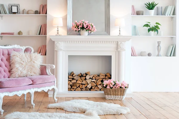 Nowoczesne światło wnętrze z kominkiem, wiosennych kwiatów i przytulna sofa różowy — Zdjęcie stockowe