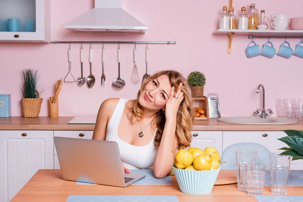 Besorgte und traurige Studentin sucht Informationen in einem Laptop online sitzt in der Küche. traurige blonde Frau, die sich wegen finanzieller Probleme gestresst fühlt und durch Finanzen arbeitet — Stockfoto