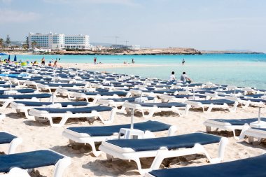 Plajda şemsiyeler ve şezlonglar bulunmaktadır. Denize yakın plastik şezlong. Tropikal tatil, yaz geçmişi.