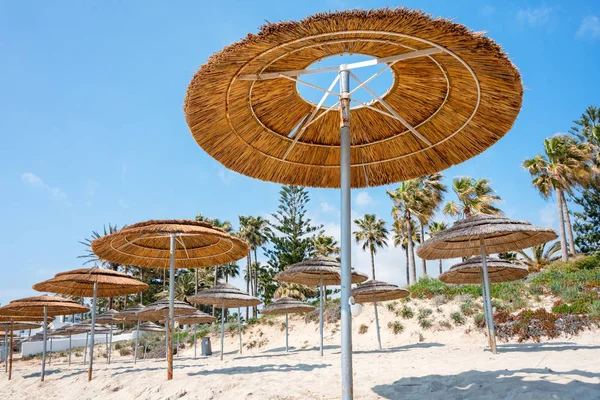 Reed parasole plażowe, osłony przeciwsłoneczne na błękitne niebo na plaży. Bambusowe parasole, parasole na białym piaszczystym tropikalnym brzegu morza. Tropikalny nadmorski brzeg morza, urlop letni. — Zdjęcie stockowe