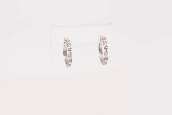 Par vita gyllene diamantörhängen på transparent stativ. Gyllene örhängen med diamanter, lyx smycken — Stockfoto