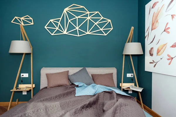 Close-up van een bed met gekleurde kussens, Bedspread en een gezellige lamp. Tijdschrift op tafel, avond lezen. Loft interieur, minimalistische Scandinavische stijl. — Stockfoto