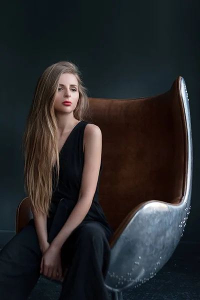 Blonde woman sitting in a chair in art nouveau style. Business, elegant businesswoman. Dark portrait. Interior, furniture — Stock Photo, Image