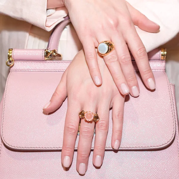 Woman hands with manicure and luxury jewelry rings. Close up of trendy leather pink bag with female hands showing fashion jewelry at camera. Concept of manicure and fashion. — Stock Photo, Image