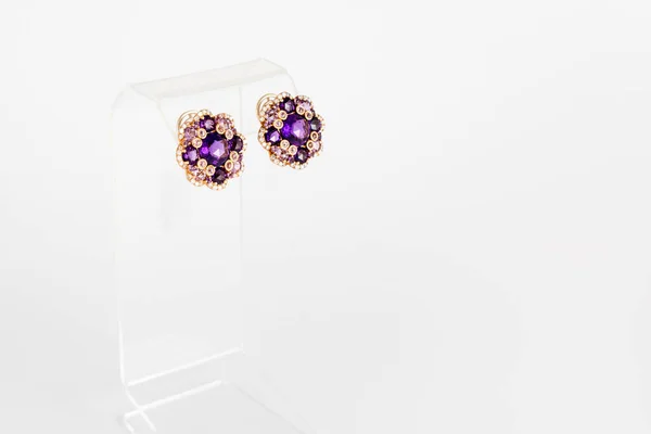 White golden earrings with diamonds and violet precious gems on light background. Long golden earrings. Fashion luxury accessories. — Stock Photo, Image