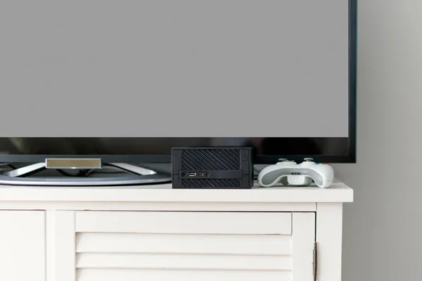 Televisor LCD plano en armario blanco en la sala de estar con pared gris oscuro. Videoconsola y gamepad. Gamer mockup estación — Foto de Stock