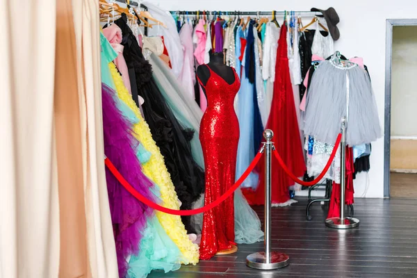 Many ladies evening gown long dresses on hanger in the dress rent shop for the wedding day or photo session. Dresses rental concept. Selective focus. Ball gown rental concept.