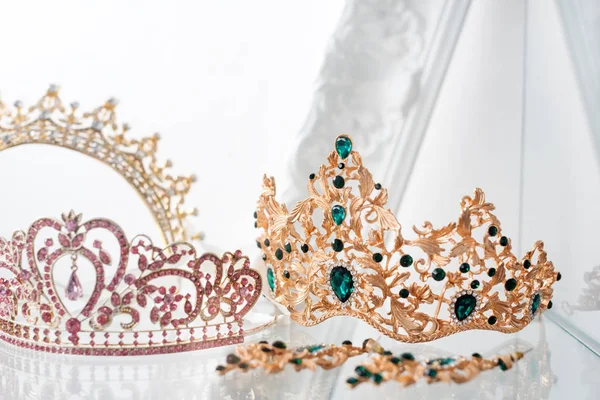 Royal luxury gold and silver crowns decorated with precious stones. Diamond tiaras with gemstones for prom and wedding. Selective focus.