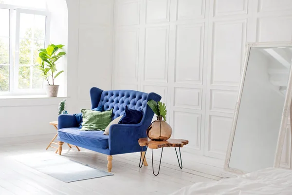 Comfortabele klassieke blauwe bank met kussens en houten salontafel in eenvoudig wit appartement — Stockfoto