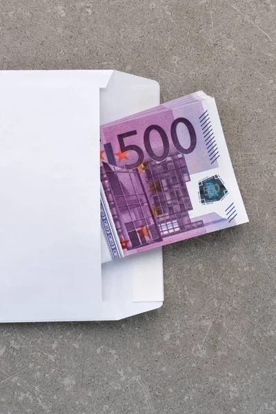 Vitt kuvert med 500 eurosedlar. Stack med femhundra eurosedlar i öppna kuvert på betong. Sedlar vikta i ett kuvert som present. Skicka eller spara pengar, korruption koncept — Stockfoto