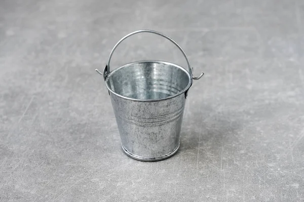 Empty small metal bucket isolated on a concrete background. Copy space. Horizontal view.