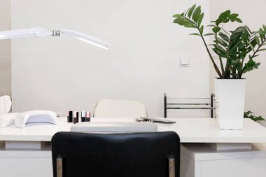 Boş modern manikür ve güzellik salonu. Lambalı uzun masa, manikür işi.