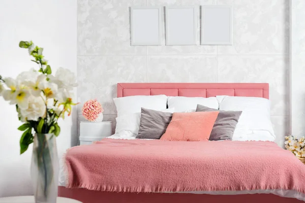 Stijlvol interieur van moderne slaapkamer. Wit en roze design van gezellige slaapkamer met bloemen. King-size bed met roze en grijze beddengoed — Stockfoto