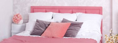 Modern yatak odasının iç dekorasyonu. Çiçekli, rahat yatak odasının beyaz ve pembe tasarımı. Pembe ve gri yataklı büyük boy bir yatak.