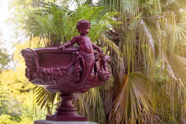 Aşk tanrısı çiçekli heykel. Portekiz, Porto botanik bahçesinde heykelleri olan Roma saksısı.