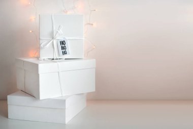 Yeni yıl hediyeleri, arka planda beyaz kutular ve kış tatili süslemeleri. Hediye kutularıyla Noel arkaplanı. Noel hediyeleri, kış mevsimi kutlaması. Metin için kopyalama alanı.