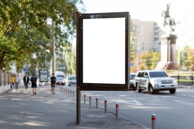 Şehrin arka planındaki dikey sokak afişlerinin boş maketi. Yolun yanındaki kaldırımda reklam için boş reklam panosu.