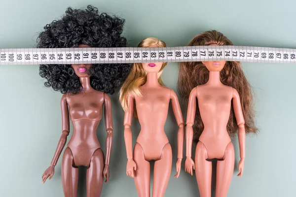 Dolls with measuring tape. Unrecognizable fashion dolls, weight loss concept. Fasting, weightloss and slimming. Diet, anorexia, eating disorder, overeating control, fight for perfect fit body. — Stock Photo, Image